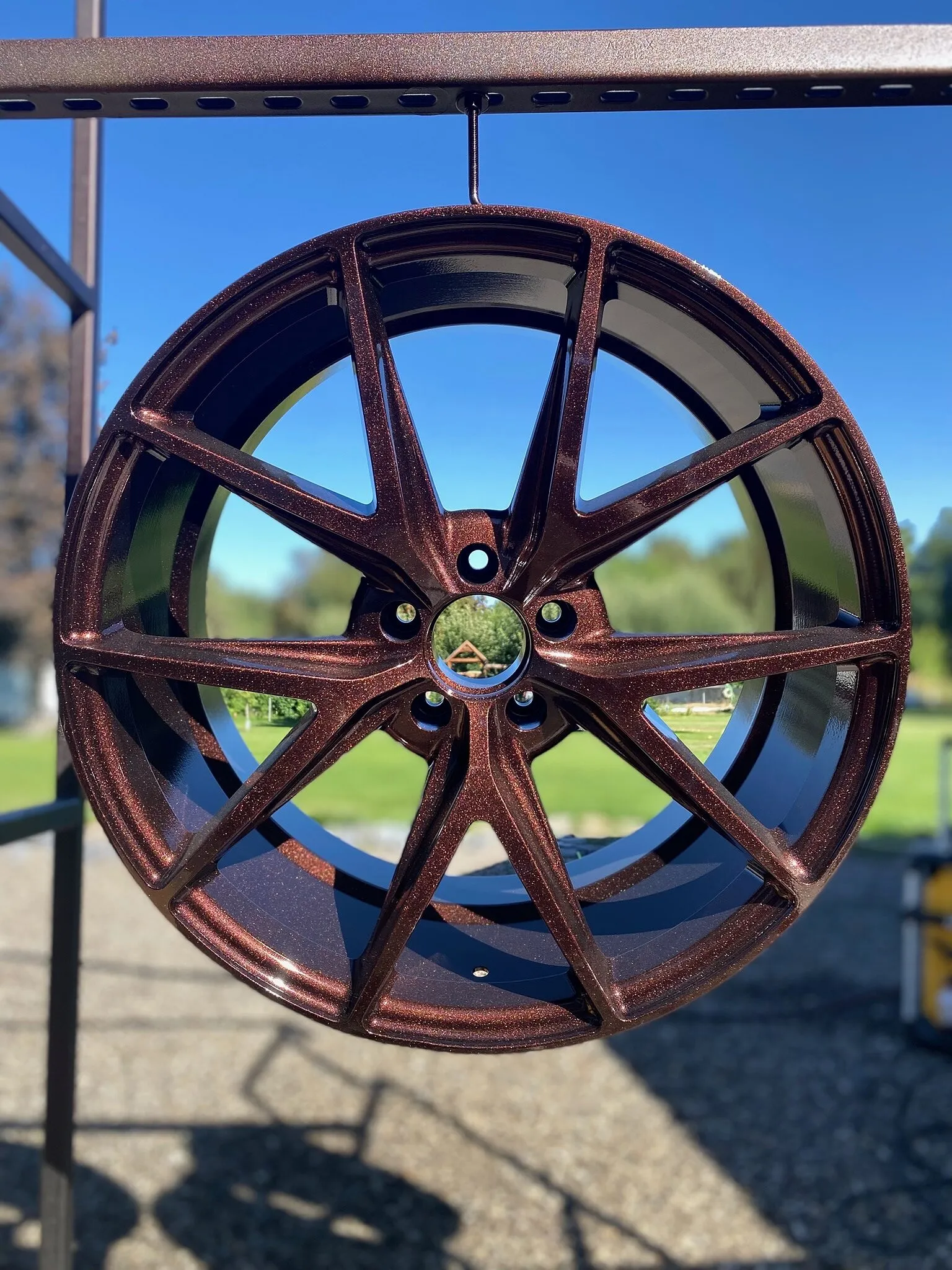 Copper metal-flake powder-coated wheel hanging on an outdoor rack, seen face on