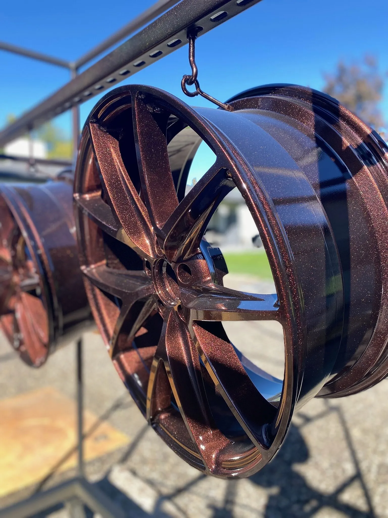 Copper metal-flake powder-coated wheel on the outdoor rack, seen from the side, with a second wheel behind it