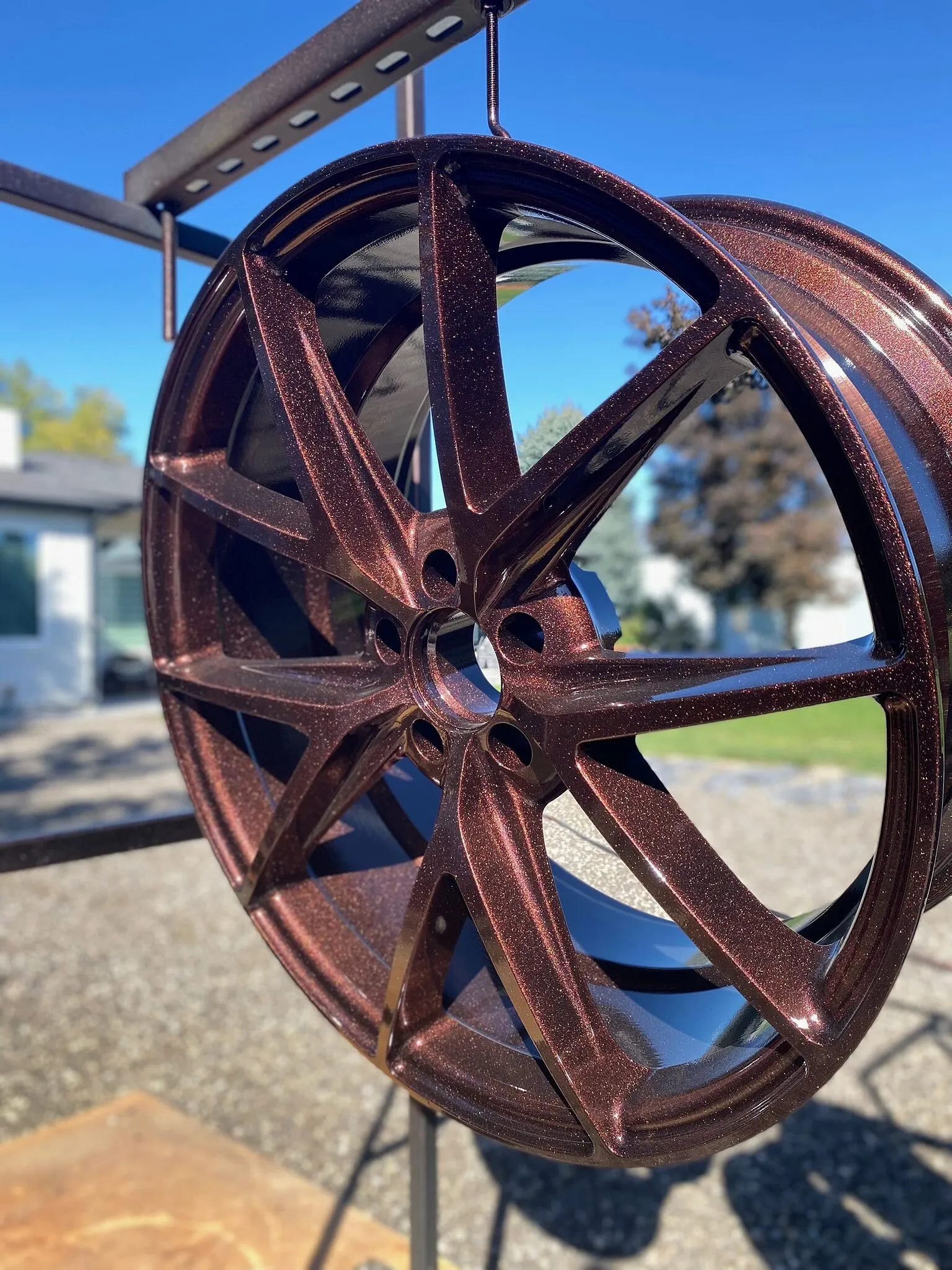 Copper metal-flake powder-coated wheel hanging on an outdoor rack under a blue sky