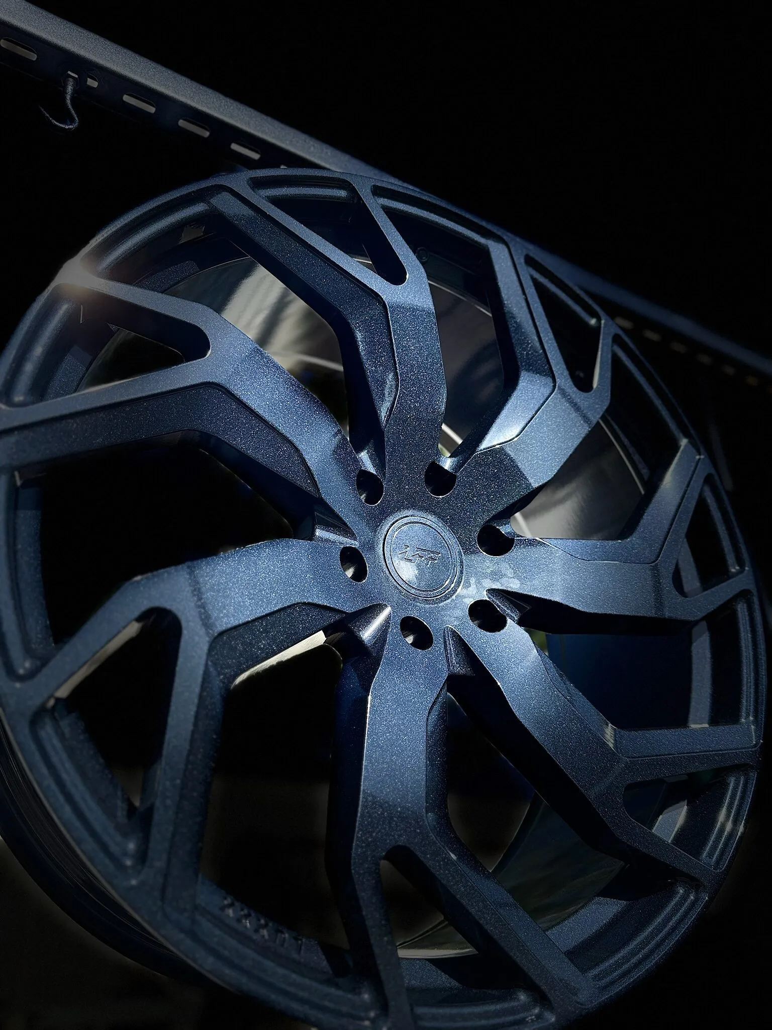 Wheel powder coated in a dark textured metallic finish, against a dark background