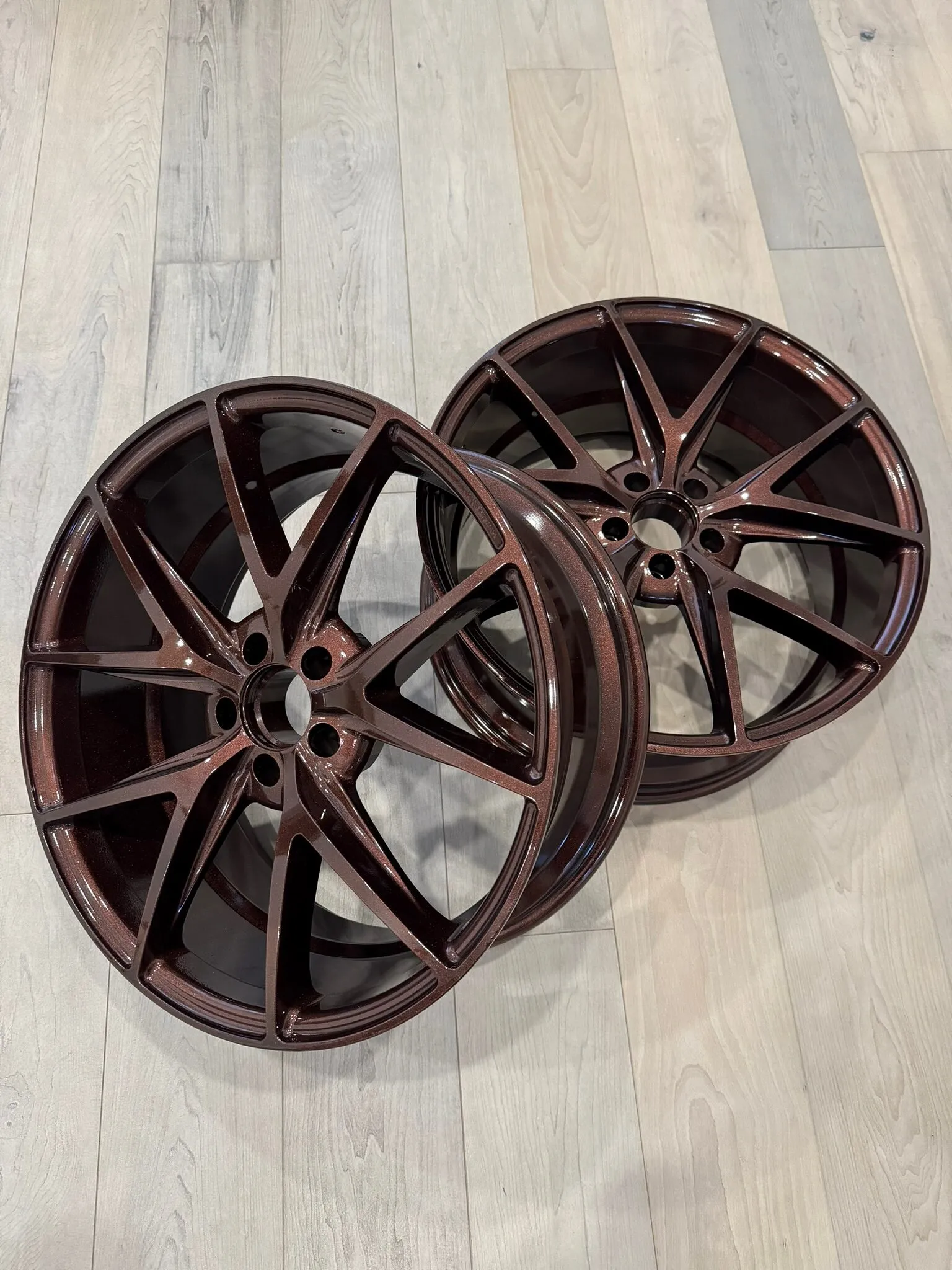 Pair of wheels powder coated in gloss bronze, standing on a wood floor