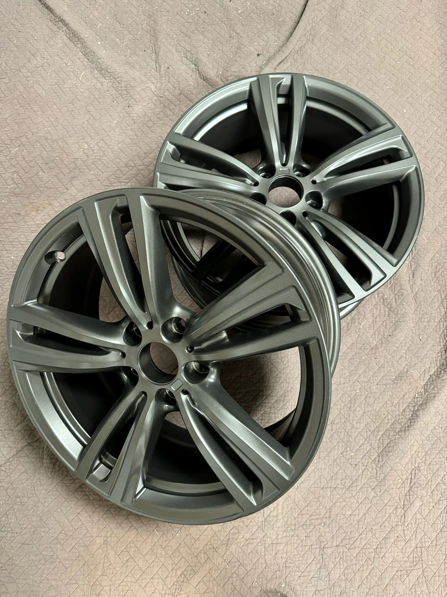 Pair of wheels powder coated gunmetal gray, laid on a canvas sheet