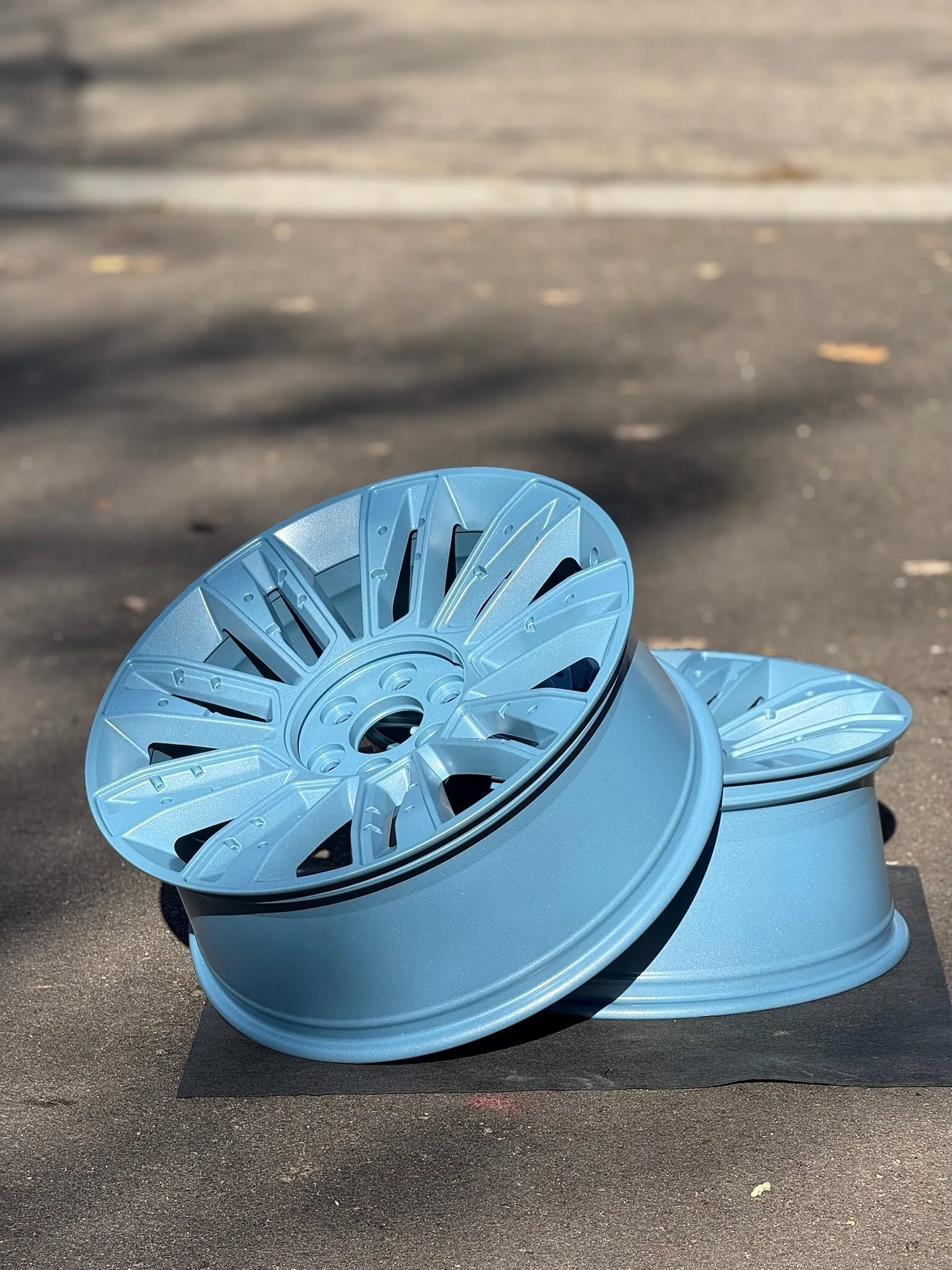Pair of wheels powder coated light blue, outdoors in the sun