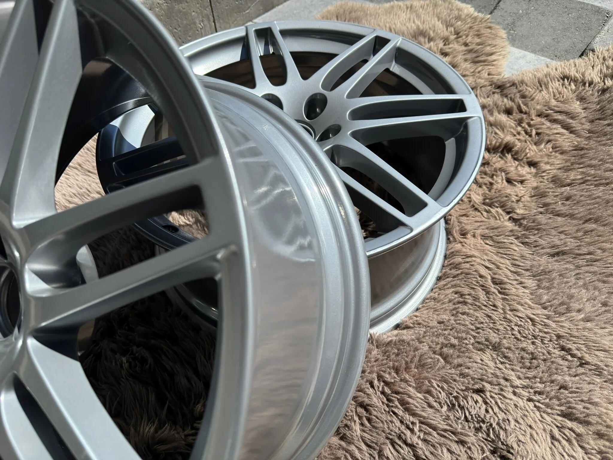 Pair of wheels powder coated silver, resting on a rug